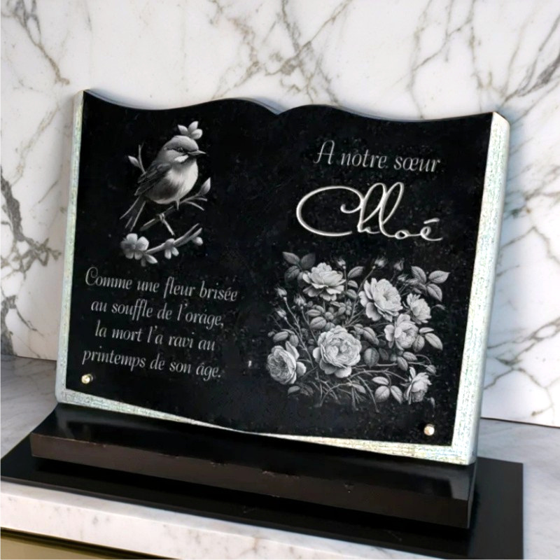 Plaque funeraire livre en granit et socle avec fleurs et oiseau.